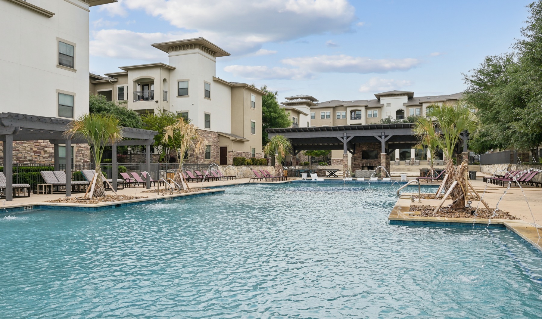 Large sparkling blue pool with a large deck and lounge chairs 
